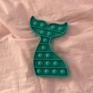 Mörkturkos fidget toy 💞🍬💞 - Bilderna visar en grön pop it-leksak i form av en sjöjungfrustjärt med små sjöjungfrumotiv på bubblorna. Produkten är i gott skick utan synligt slitage. Perfekt för stresslindring eller som sensorisk leksak ✨💅✨🍬💞🍬