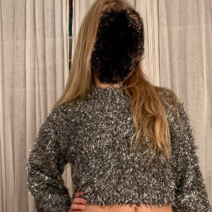 Glittrig croppad tröja från Zara ✨✨✨🩶🩶🩶 - Säljer en croppad långärmad tröja från ✨Zara✨ i silver med glittrigt material. Tröjan har en fluffig, festlig look och är perfekt för dig som vill sticka ut. Den har rund hals och är supermjuk och bekväm att bära ✨🩶✨