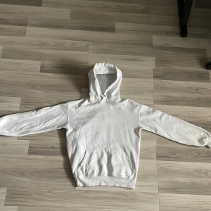 Vit hoodie med huva och ficka - Vit hoodie från Junkyard. med klassisk huva och stor magficka framtill. Tröjan har långa ärmar med ribbade muddar och är gjord i mjukt bomullsmaterial. Perfekt för chill dagar och enkel att matcha med jeans eller joggers.