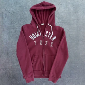 Hollister Hoodie - Sjukr snygg Hollister Hoodie i en grym vinröd färg. Storlek S. Längd: 64, bredd: 48, arm: 62. Modellen är 176, 59kg. Urtvättad men syns enligt mig bara på närhåll. Perfekt för hösten🍁