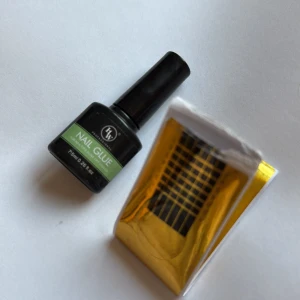 Nagellim och nagelformar - Nagellim från TK Professional i svart flaska med grön etikett, 7,5 ml. Medföljer gör ett ark med guldiga nagelformar för att bygga eller förlänga naglar. Perfekt för dig som gillar att fixa naglarna hemma.