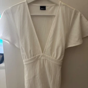 Vit omlottklänning från Gina Tricot - Supersöt vit blus från Gina Tricot med v-ringning och knyt i midjan. Aldrig använd och normal i storleken 