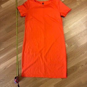 Korallröd kort klänning Rut&Circle XS - Enkel och snygg korallröd kortärmad klänning från Rut&Circle i storlek XS. Rak modell med rund halsringning. Perfekt för dig som gillar färg och vill ha en bekväm och stilren look.