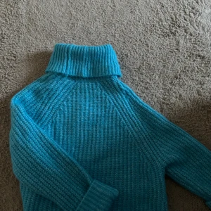 Turkos stickad polotröja från Zara - Säljer en turkos stickad polotröja med grov ribbstickning och hög krage. Tröjan har lång ärm och är perfekt för dig som vill ha en mysig och färgstark look. Passar grymt till jeans eller kjol för en chill vibe. FRÅN ZARA