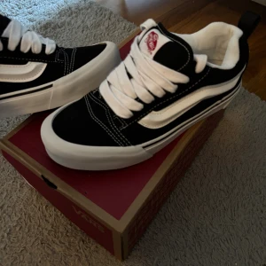 Svarta och vita Vans Old Skool sneakers - Klassiska Vans Old Skool sneakers i svart och vitt med ikonisk sidorand. Skorna har vit platt sula, snörning och kontrastsömmar. Ovandelen är i mocka och canvas för en skön och cool look. Perfekta för dig som gillar streetstyle och skatekänsla. Aldrig använda 38/39strlk