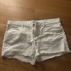 Shorts Calliope (italian brand) - Snygga vita shorts från Calliope med råa kanter och slitningar. Ena sidan har en cool spetsdetalj som ger extra edge. Klassisk femficksmodell med dragkedja och knapp. Perfekta för en trendig sommarlook.