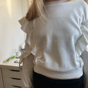 Vit volangtröja från H&M - Vit tröja från Hm med volanger på ärmar och mage. Storlek 134/140