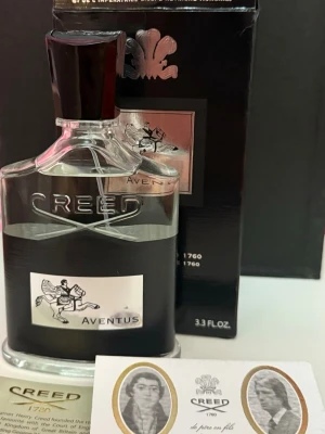 Creed Aventus Eau de Parfum 100ml - Creed Aventus är en exklusiv parfym i en elegant glasflaska med svart och silverdetaljer. Flaskan rymmer 100 ml och har en stilren etikett med en ryttare. Levereras i original svart förpackning med silverlogga och märkets klassiska emblem.