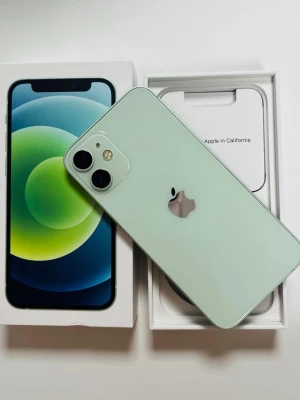 iPhone 12 mini grön 64GB - Snygg grön iPhone 12mini med 64GB lagring. Telefonen har en stilren design med platt glasbaksida och aluminiumram. Utrustad med dubbla kameror och Apples klassiska logga på baksidan. Kommer i originalkartong med tillbehör.
