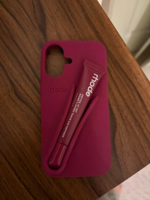 Rhode mobilskal och läppbalsam - Burgundy fall edition mobilskal från rhode med  hållare för läppbalsam på baksidan. Läppbalsamet är rasberry jelly. Skalet är till iPhone 16 :) helt nytt