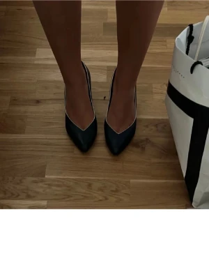 Svarta klassiska pumps med spetsig tå - Snygga svarta pumps med spetsig tå och låg klack. Skorna har en stilren design och passar perfekt till både jeans och klänning. Tillverkade i ett slätt material som ger en elegant look.