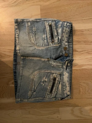 Jeanskjol  - Ljus blåa jeanskjol med coola dragkedjor och två knappar 