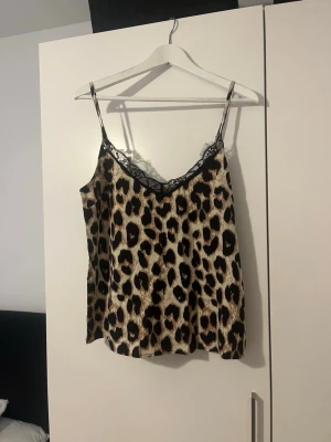 Leopardmönstrat linne med spets - Säljer ett leopardmönstrat linne med tunna axelband och svart spetsdetalj vid urringningen. Antingen som en sov tröja eller som en chill tröja