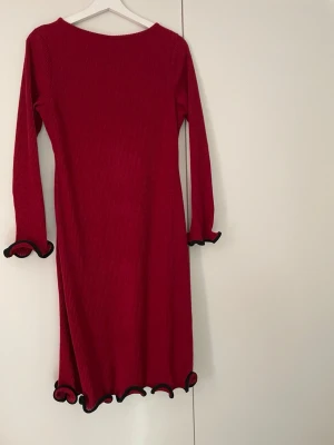 Röd ribbad klänning med volang - Röd ribbad långärmad klänning med svarta volangdetaljer vid ärmslut och nederkant. Klänningen har en kroppsnära passform och är tillverkad i ett stretchigt material som ger en bekväm känsla. Perfekt för dig som vill sticka ut med en färgstark look. Från SHEIN.