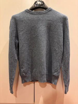 Ljusblå stickad tröja - En enkel och stilren ljusblå stickad tröja med rund halsringning och lång ärm. Tröjan har diskret struktur i materialet och passar perfekt till både jeans och kjol. Snygg att bära lager på lager under kallare dagar.