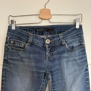 Blå lågmidjade bootcut jeans från ONLY - Snygga blå jeans från ONLY. Storlek W27 L34 (en XS-S). Midjemått: 40 cm. Innerbenslängd: 82 cm. 
