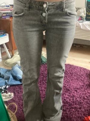 Gråa jeans💕 - Gråa jeans ifrån Gina tricot som har knappar istället för dragkedja vid gylfen. Dom är lågmidjade och bootcut, nästan aldrig använda. Passar mig bra som är 165 och har storlek 26 ungefär i jeans💕