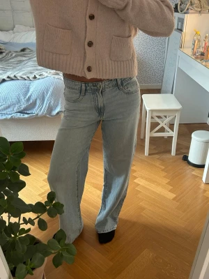 Ljusblåa raka jeans med hög midja - Säljer ett par ljusblå jeans med rak passform och låg midja. Jeansen har klassiska fem fickor och subtila slitningar för en avslappnad vibe. Perfekta till en stickad tröja eller crop top för en chill look.