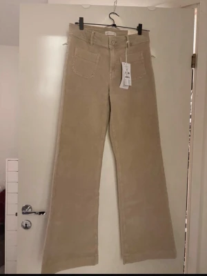 Beiga utsvängda manchesterbyxor - Snygga beiga manchesterbyxor från Gina Tricot med utsvängda ben och hög midja. Byxorna har framfickor och bälteshällor, perfekta för en trendig och avslappnad look.