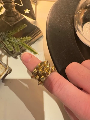 Bred guldfärgad ring med nitar - Säljer denna guldiga ringen från Edblad pågrund utav för liten, stl 16,00 mm (xs) inga defekter mycket fint skick!! Kontakta för fler bilder eller frågor!! 