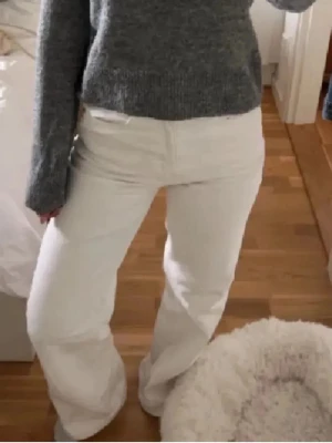 Vita raka jeans  - Säljer ett par vita jeans med rak passform. Jeansen har klassisk femficksdesign och stängs med dragkedja och knapp. Perfekta för en clean och stilren look. Materialet ser ut att vara bomull eller bomullsblandning.