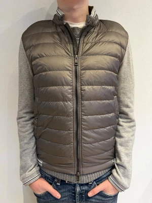 Moncler cardigan grå - Säljer en riktigt fet cardiganjacka från Moncler i grått med quiltad, dunfylld front och mjuka, ljusgrå ärmar. Jackan är i storlek M men passar även S och dragkedja framtill och Moncler-logga på ärmen. Självklart äkta! Skriv vid funderingar eller frågor🙌✅