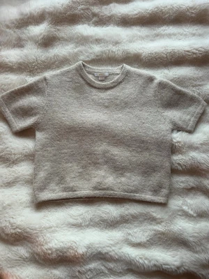 Beige stickad t-shirt Gina Tricot - Kortärmad stickad t-shirt i mjuk beige ullmix från Gina Tricot. Tröjan har rund halsringning med ribbad kant och en enkel, rak passform. Är i storlek 146/152💗