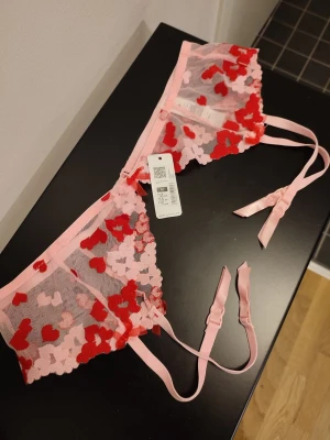 Vacker strumpebandshållare i spets - Vecker strumpebandshållare i spets med rosa och röda hjärtan på. Storlek M. Helt ny med prislapp kvar. Köpt på Cubus. Perfekt för alla hjärtans dag? 💕❤️