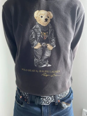 Svart hoodie Bear Ralph Lauren - Svart hoodie från Ralph lauren med den klassika björnen på. Den passar perfekt in i dom flesta garderoberna. Storleken är 10-12/155 modellen är 157cm. Nypris 1500kr mitt pris 500kr. Pris går att diskuteras vid snabb affär!