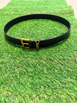 Svart skärp från Yves Saint Laurent - Snyggt svart skärp från Yves Saint Laurent med guldfärgat YSL-logo och spänne. Skärpet är smalt och stilrent, perfekt för att lyfta vilken outfit som helst. Tillverkat i slätt skinn för en exklusiv känsla.