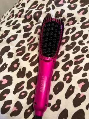 Rosa elektrisk värmeborste DSP - Elektrisk värmeborste från DSP i metallicrosa färg. Borsten har svarta piggar och flera knappar för inställningar på handtaget. Perfekt för att styla och räta ut håret snabbt och smidigt. Tillverkad i plast och metall.