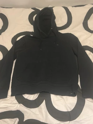 Svart hoodie - En skön svart hoodie med snörning och en stor ficka i storlek M men har en mindre passform som då passar bättre på storlek XS-S. Hoodien är bara använd ett par fåtal gånger och jag säljer den då den är för liten. Nypris ca 450kr. Skriv gärna om du har någon fråga!