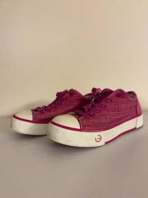 Rosa varma sneakers med vit sula från UGG - Snygga rosa sneakers med vit tå och sula samt rosa detaljer från UGG. Skorna har lågt skaft, klassisk snörning och är tillverkade i tygmaterial. Perfekta för dig som vill sticka ut med färg på fötterna. Skorna är mindre än 39 och mer som 38.