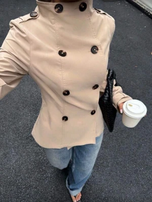 Beige trenchcoat från Muchica - Stilren beige trenchcoat från Muchica med dubbelknäppning och högt krage. Den är varm och mysig och bara använd en gång. Skriv till mig om ni vill ha mer bilder på jackan💕