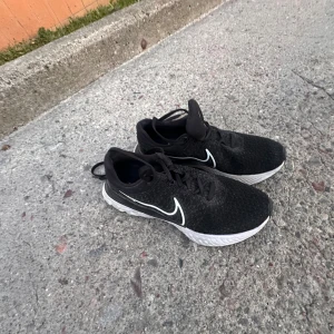 Svarta Nike sneakers med vit sula - Svarta Nike sneakers med vit sula och klassisk vit swoosh på sidan. Ovandelen är i mesh-liknande syntetmaterial som andas och har snörning för bästa passform. Perfekta för dig som gillar sportig och stilren look.