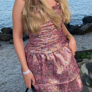 Metallic minidress från LoveShackFancy - Superfin glittrig rosa kortklänning från LoveShackFancy med metallicskimmer och volangdetaljer upptill. Klänningen har axelbandslös design. Använd en gång på min födelsedag! 