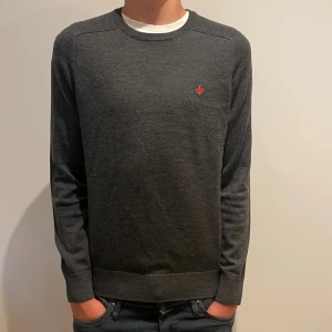 Stickad tröja - Snygg mörkgrå stickad tröja från Morris med rund halsringning och diskret röd logga broderad på bröstet. Tröjan har lång ärm och ribbade muddar vid ärmslut och nederkant. Perfekt för lager-på-lager och stilren look.                          Svarar snabbt samt fraktar samma dag köp!         Bara att skriva om du har några funderingar!