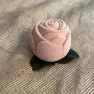 Ring hållare ros formad i rosa💘 - Supergullig smyckesask i form av en rosa ros med sammetsyta och gröna tygblad. Perfekt för att förvara en ring eller ett litet smycke. Insidan är klädd i vitt tyg och har plats för en ring. Söt detalj på sminkbordet eller som presentask. Kostar 20 kr + frakt