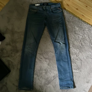 Replay Grover jeans i ljusblå denim - Säljer ett par Replay Grover jeans i ljusblå tvätt med klassisk femficksdesign och snygga detaljer på fickorna. Jeansen har raka ben och slim passform, tillverkade i mjuk bomullsdenim. Perfekta för dig som gillar stilrena och bekväma jeans. Har inte använt de så mycket så väldigt bra skick🤩