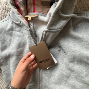 Grå hoodie från Burberry med dragkedja - Det enda är att den blivit tvättad så att den är S även fast det står att det är M försöker sälja snabbt