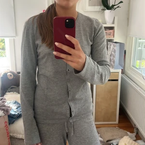 Grå kofta med knappar - Mysig grå kofta med långa ärmar och knäppning framtill. Enkel och stilren design som passar perfekt till chill dagar hemma eller när du vill ha en clean look. Tillverkad i mjukt material som känns skönt mot huden.