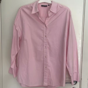 Ljusrosa skjorta från Studio - Säljer en stilren ljusrosa skjorta från Studio. Skjortan har klassisk krage, långa ärmar med manschett och knappar framtill. Tillverkad i mjuk bomull som känns skön mot huden. Perfekt för dig som gillar en clean och fräsch look.