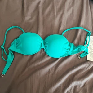 Turkos bikiniöverdel  - Turkos bikiniöverdel från spanien. Axelbanden är justerbara och knäpps i ryggen med spänne. Snygg och enkel modell som ger bra stöd och passar perfekt till stranden eller poolen. De har även lite push-upp som man ser på andra bilden, aldrig använda, har kvar etiketter. perfekt till semestern