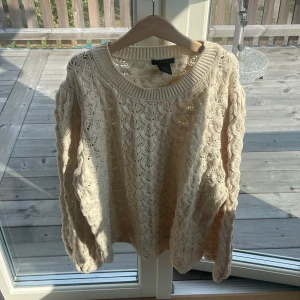 Beige stickad tröja från Lindex - Säljer en beige stickad tröja från Lindex i storlek M. Tröjan har ett snyggt virkat mönster och rund halsringning. Perfekt för lager-på-lager och ger en chill vibe till din outfit.