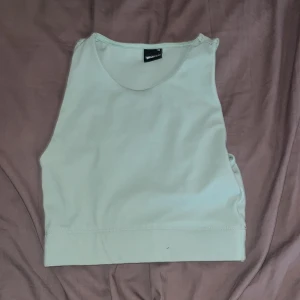 Ljusgrön linnetopp  - Säljer en stilren ljusgrön linnetopp från Gina Tricot. Toppen är ärmlös med rund halsringning och har en croppad passform. Perfekt att matcha med höga jeans eller kjol för en fräsch look. Materialet är mjukt och stretchigt för extra komfort. Kan även fungera som träningstopp