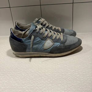Philippe Models - Snygga Philippe Models sneakers i blått och gråa detaljer med paneler i mocka och textil. Skorna är väl använda med små defekter framförallt på undersidan, men är i bra skick och har mycket mer att ge.
