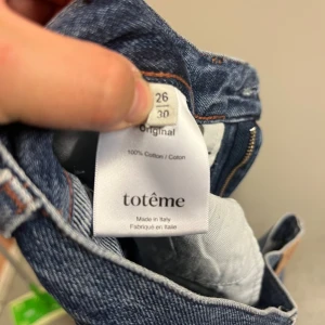 Blå jeans från Totême i bomull - Klassiska blå jeans från Totême, tillverkade i 100% bomull. Snyggt skurna med raka ben och detaljerade med kontrastsömmar och läderpatch med logga bak. Behövs några stygn i en hälla. 