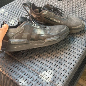 Svarta Adidas sneakers med chunky sula - Svarta Adidas sneakers med klassiska tre ränder på sidan och chunky sula. Skorna har snörning, dragflik baktill och ovandel i syntet och textil. Snygg urban look med robust design, perfekta för dig som gillar streetstyle.