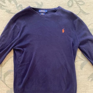 Mörkblå tröja Polo Ralph Lauren M - Mörkblå långärmad tröja från Polo Ralph Lauren i slim fit-modell. Tillverkad i mjuk pima bomull och pryds av den klassiska röda broderade loggan på bröstet. Perfekt för dig som gillar stilrena och tidlösa plagg. Pris kan diskuteras 