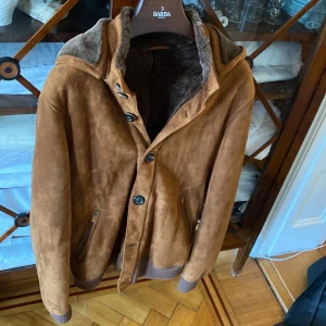 Fratelli Rossetti mocka jacka med päls - KOM MED BUD. INTE UNDER 5k. Fratelli Rossetti mocka jacka som är lined med riktig päls. Nypris är en bra bit över 18,000kr. Gjord för dig som vill uppleva den absolut högsta nivån av italienskt hantverk. Perfekt för lite kyligare dagar, fungerar även på kalla vinterdagar. Storlek 50 passar M/L. Det ingår ett skynke för den och en kemtvätt rekommenderas. Luvan kan tas av. 